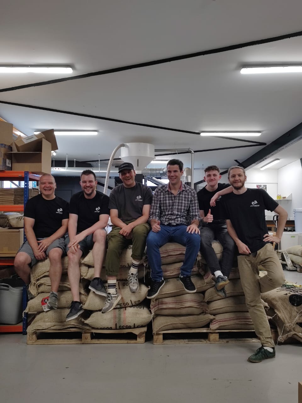 Athos, our coffee farmer in Brazil with the EA Team sat on coffee sacks